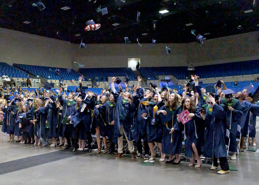 a photo of students tossing their graduation caps in the air during a commencement ceremony