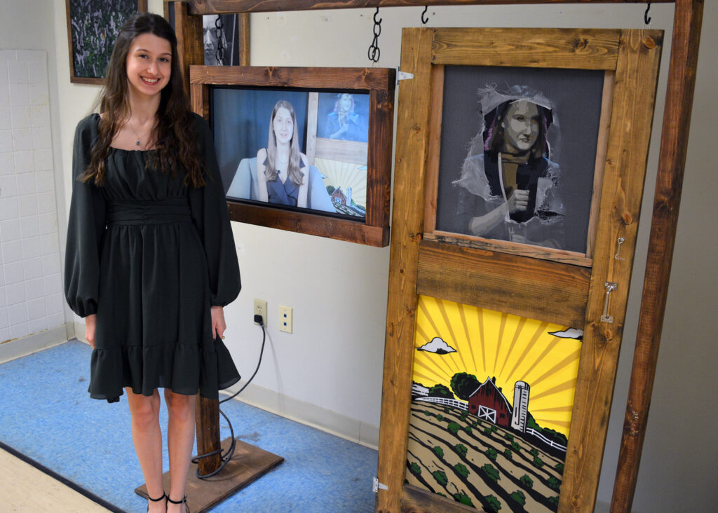 a female student with an art and film display that she created